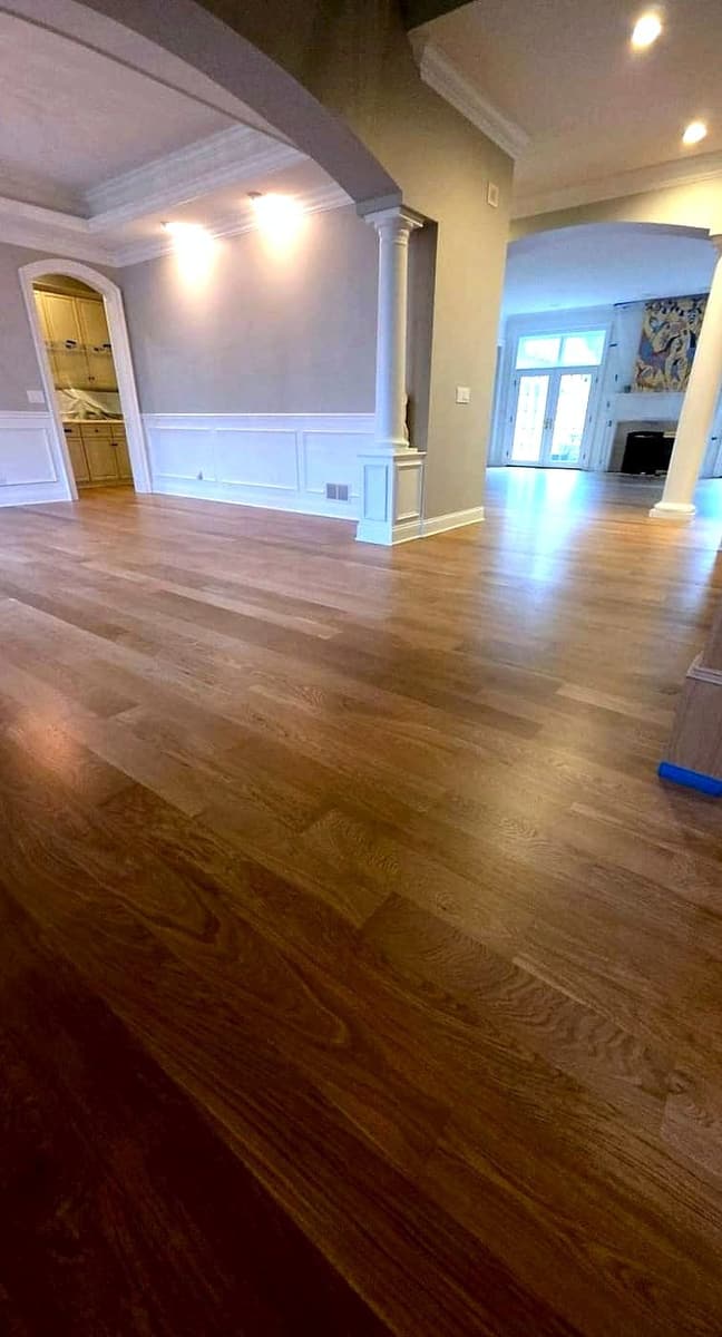 Light oak hardwood flooring through an open-concept living area with arched entryways, completed by Gusjov Flooring
