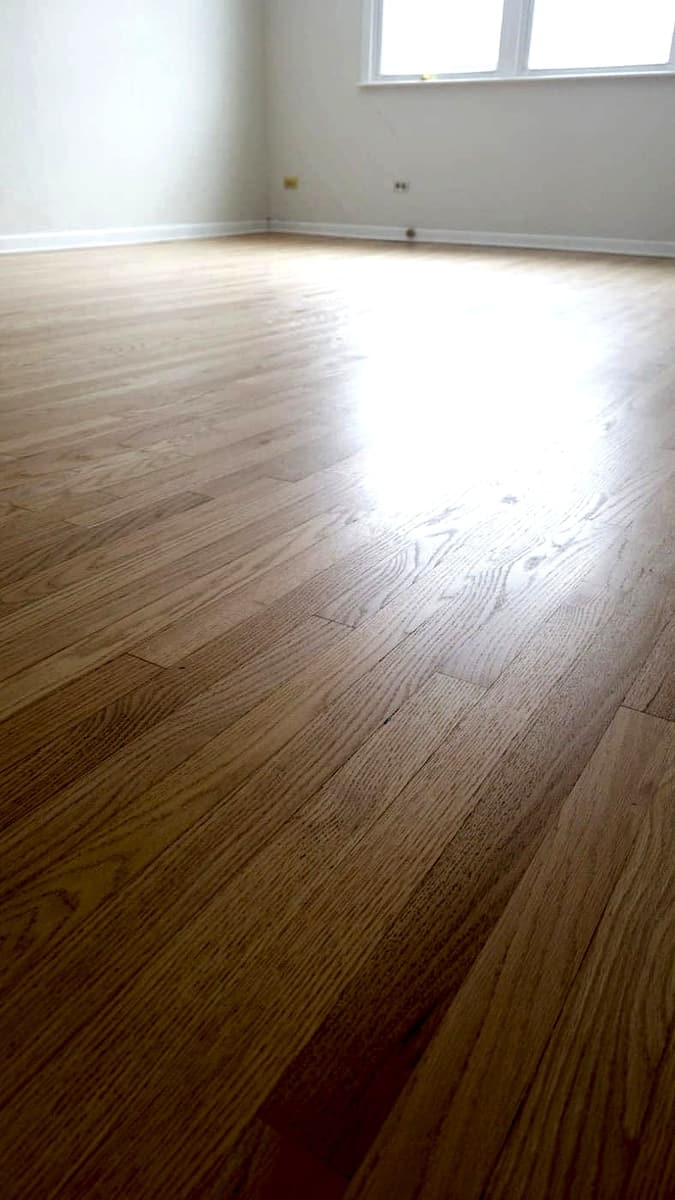 Natural light oak hardwood planks in an empty room with a window