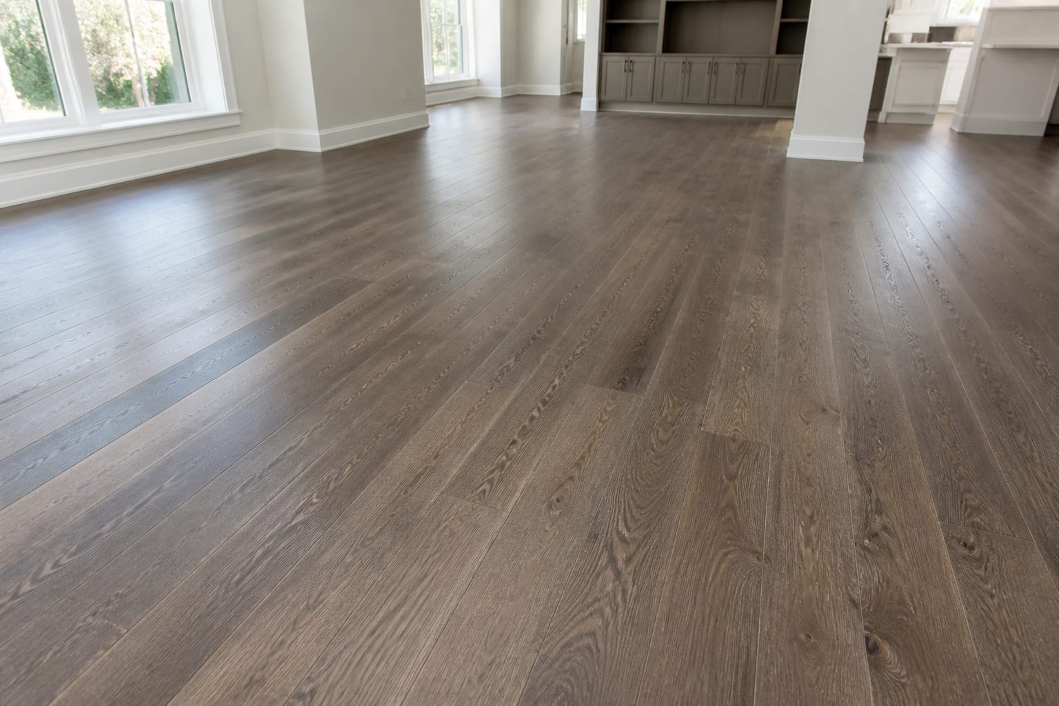 Medium oak hardwood flooring filling a bright empty living room